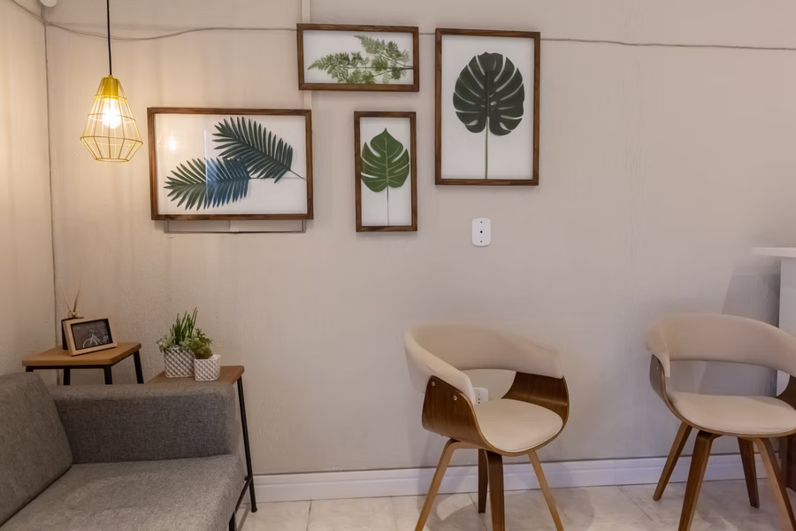 Sala de espera da Clínica Haiquel Abjaude com sofá e quadros emoldurados